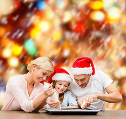 Image showing happy family in santa helper hats making cookies