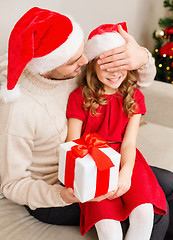 Image showing smiling father surprises daughter with gift box