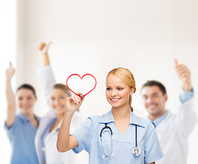 Image showing smiling doctor or nurse drawing red heart