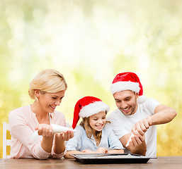 Image showing happy family in santa helper hats making cookies