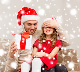 Image showing smiling father surprises daughter with gift box