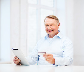 Image showing old man with tablet pc and credit card at home