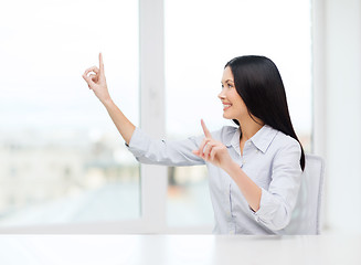 Image showing smiling woman pointing to something imaginary