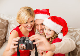 Image showing smiling family in santa helper hats taking picture