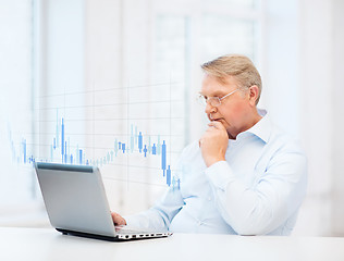 Image showing old man in eyeglasses working with laptop at home