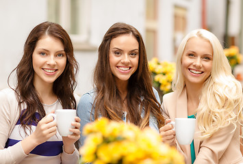 Image showing three beautiful girls drinking coffee in cafe