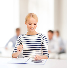 Image showing woman with notebook and calculator studying