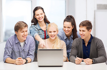 Image showing smiling students looking at laptop at school