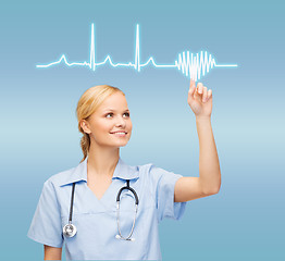 Image showing smiling doctor or nurse pointing to cardiogram