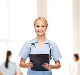 Image showing smiling female doctor or nurse with clipboard