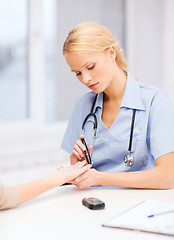 Image showing female doctor or nurse measuring blood sugar value