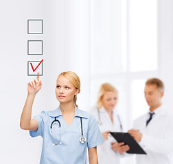 Image showing smiling doctor or nurse pointing to checkmark