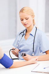 Image showing female doctor or nurse measuring blood pressure