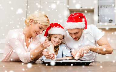 Image showing happy family in santa helper hats making cookies