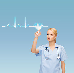 Image showing smiling doctor or nurse pointing cardiogram