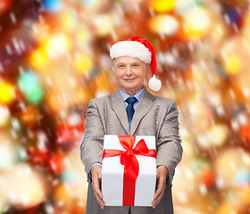 Image showing smiling man in suit and santa helper hat with gift