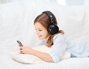 Image showing girl with smartphone and headphones at home