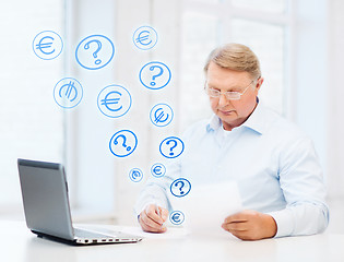 Image showing old man in eyeglasses filling a form at home