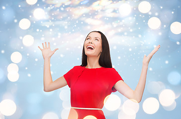 Image showing smiling young woman in red dress with hands up