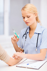 Image showing calm female doctor or nurse with syringe