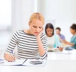 Image showing woman with notebook and calculator studying