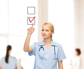 Image showing smiling doctor or nurse pointing to checkmark