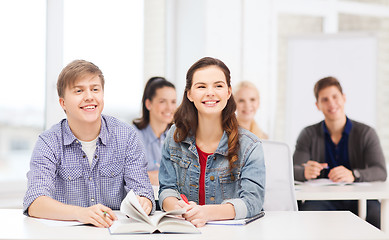 Image showing two teenagers with notebooks and book at school