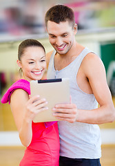 Image showing two smiling people with tablet pc in the gym