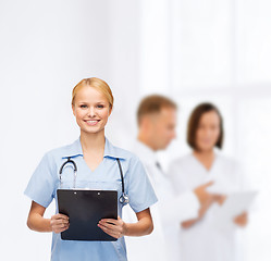 Image showing smiling female doctor or nurse with clipboard