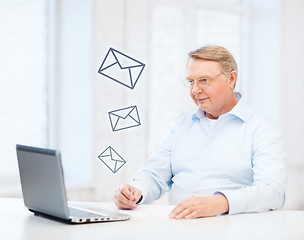 Image showing old man in eyeglasses filling a form at home