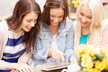 Image showing three beautiful girls looking at tablet pc in cafe