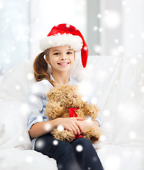 Image showing smiling girl in santa helper hat with teddy bear