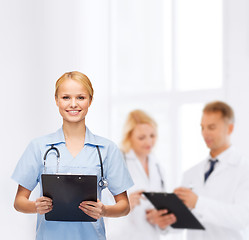 Image showing smiling female doctor or nurse with clipboard