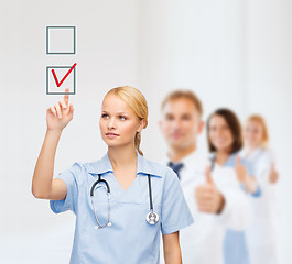 Image showing smiling doctor or nurse pointing to checkmark