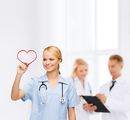 Image showing smiling doctor or nurse drawing red heart