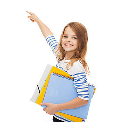 Image showing cute girl with folders pointing at virtual screen