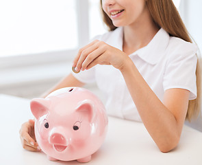 Image showing smiling child putting coin into big piggy bank