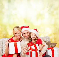 Image showing smiling family holding gift boxes and sparkles