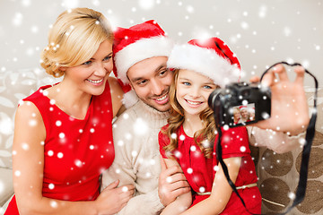 Image showing smiling family in santa helper hats taking picture