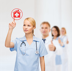 Image showing smiling doctor or nurse pointing to hospital icon