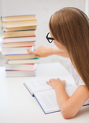 Image showing little student girl in eyeglasses with many books