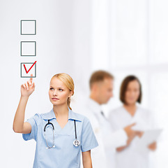 Image showing smiling doctor or nurse pointing to checkmark