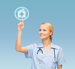 Image showing smiling doctor or nurse pointing to hospital icon