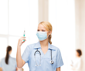 Image showing female doctor or nurse in mask holding syringe