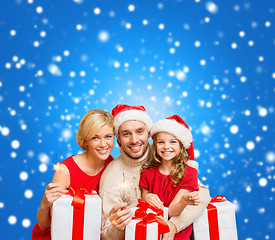 Image showing smiling family holding gift boxes and sparkles