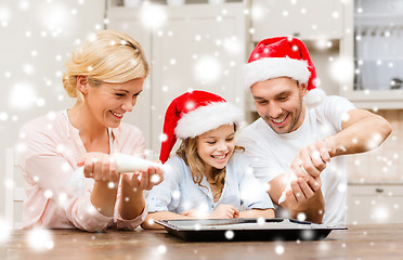 Image showing happy family in santa helper hats making cookies