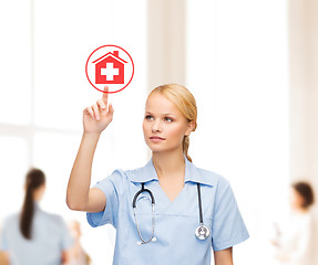 Image showing smiling doctor or nurse pointing to hospital icon