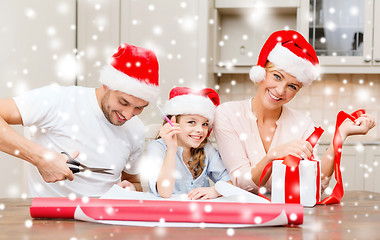 Image showing smiling family in santa helper hats with gift box