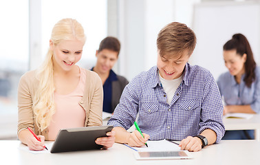 Image showing two smiling students with tablet pc and notebooks