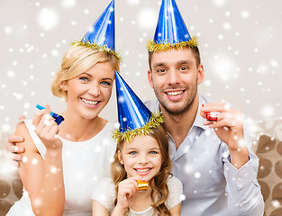 Image showing smiling family in blue hats blowing favor horns